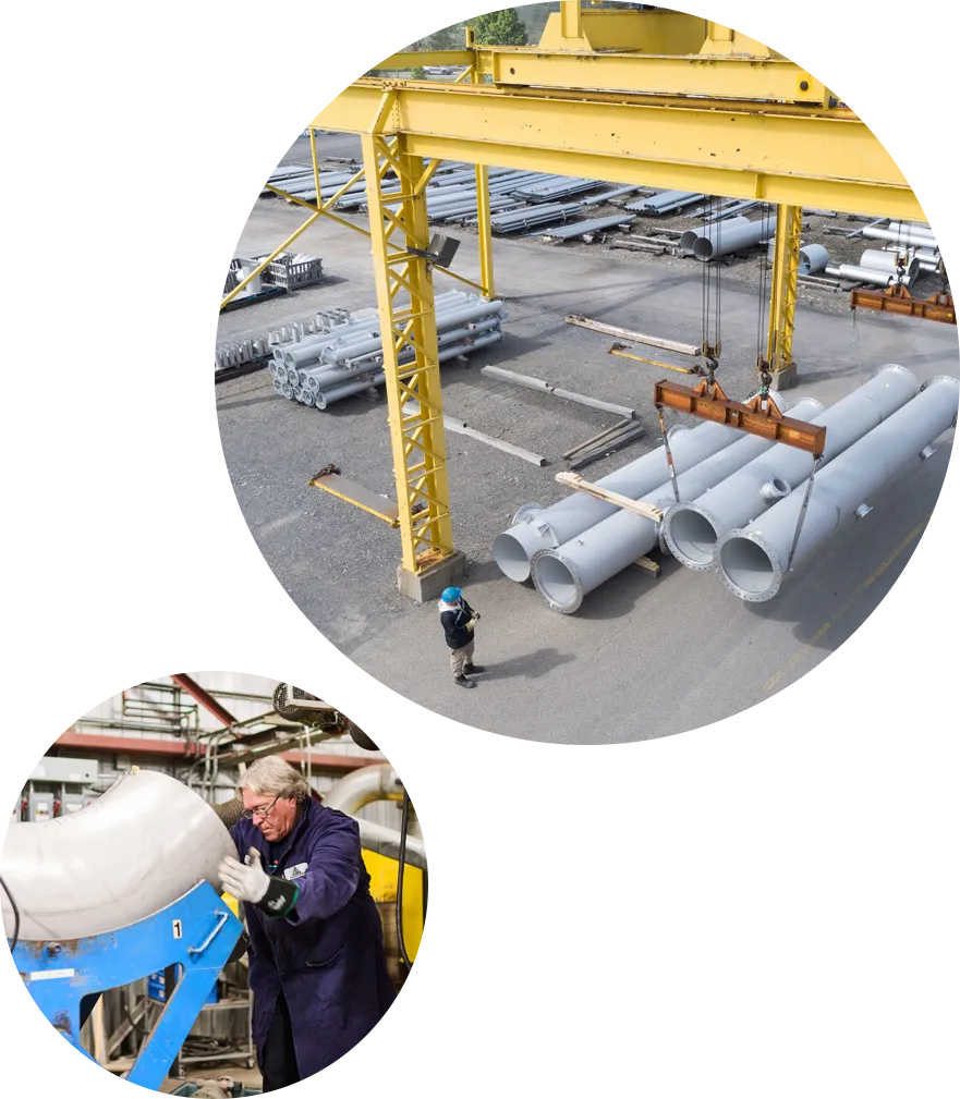 Overhead crane holding large pipes and a worker moving a piece of pipe